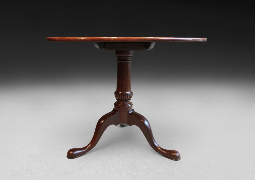 A mid-18th century mahogany tripod centre table featuring a polished circular top supported by a turned stem and three cabriole legs ending in pad feet. View V