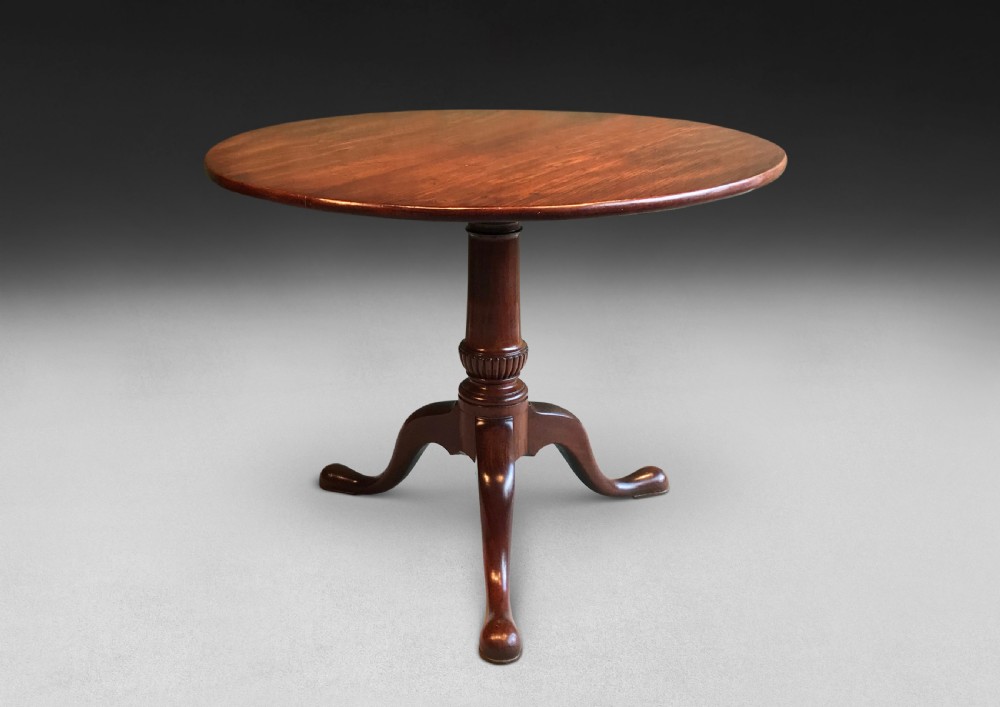 A mid-18th century mahogany tripod centre table featuring a polished circular top supported by a turned stem and three cabriole legs ending in pad feet. View VI