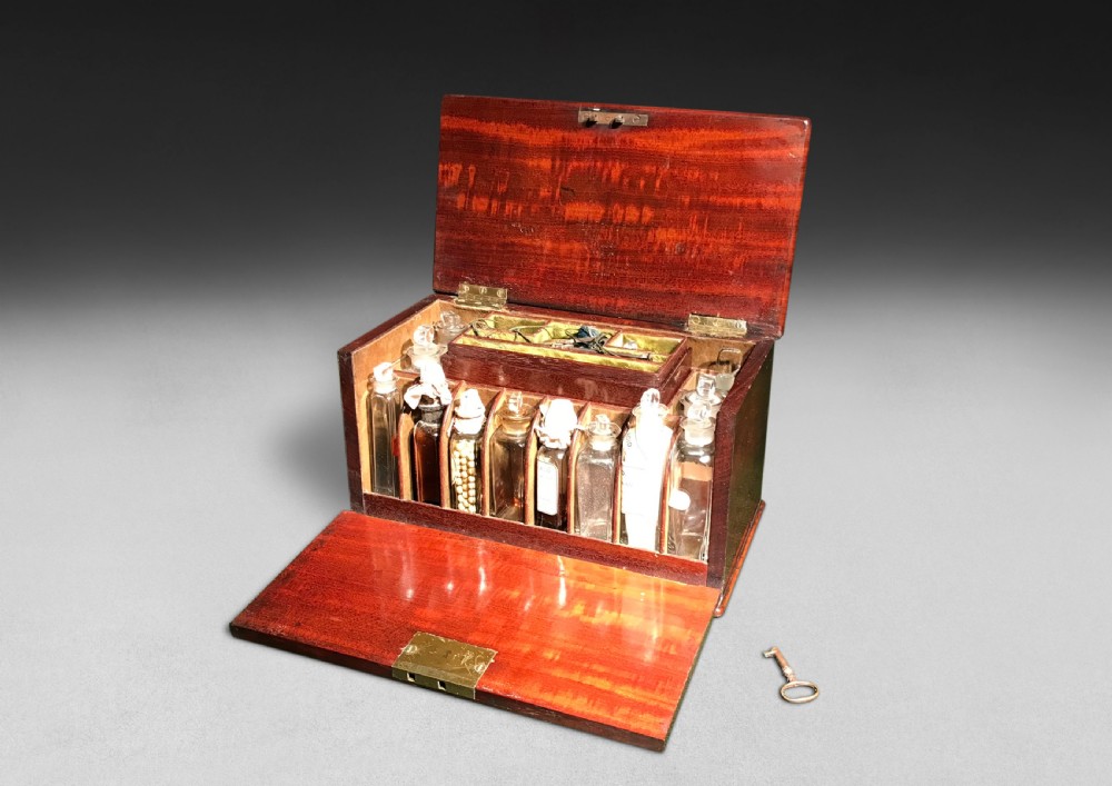 A Regency mahogany apothecary box shown open to display glass bottles, small drawers, brass fittings, and a key. View III