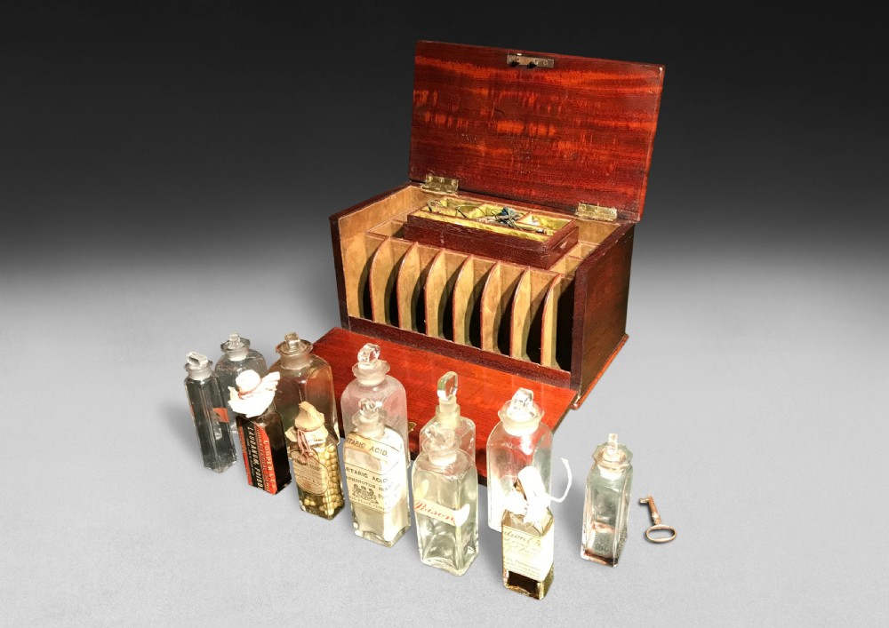A Regency mahogany apothecary box shown open to display glass bottles, small drawers, brass fittings, and a key. View V