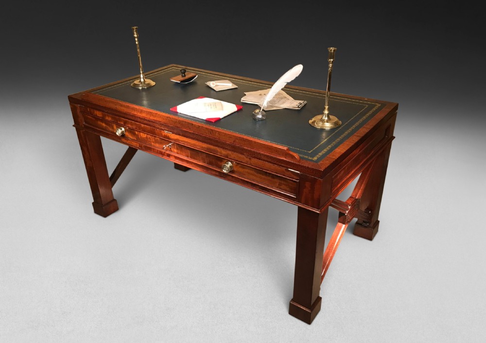A Regency mahogany library table with a leather writing surface, a low rear gallery, a frieze drawer with brass knobs, and structured end supports. View II