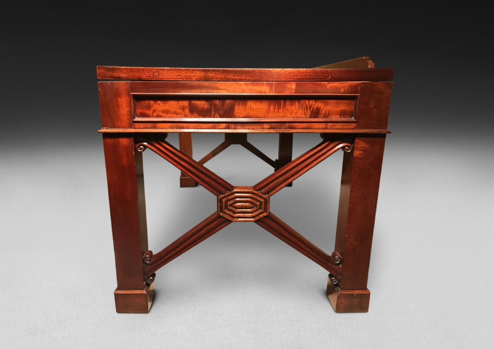 A Regency mahogany library table with a leather writing surface, a low rear gallery, a frieze drawer with brass knobs, and structured end supports. View VII
