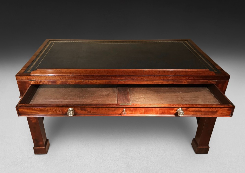 A Regency mahogany library table with a leather writing surface, a low rear gallery, a frieze drawer with brass knobs, and structured end supports. View VIII