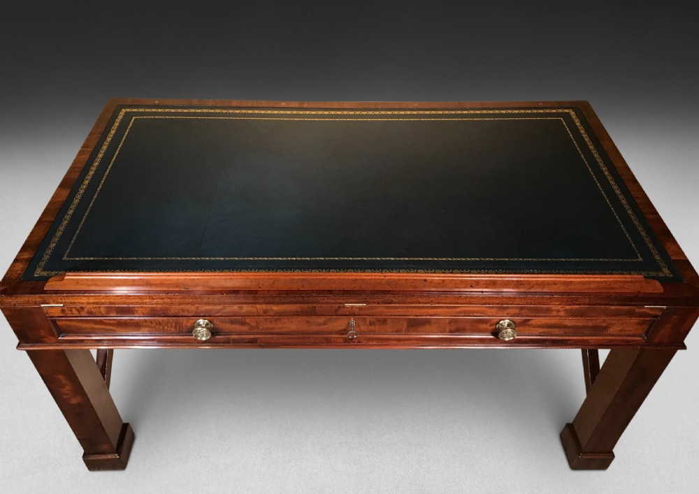 A Regency mahogany library table with a leather writing surface, a low rear gallery, a frieze drawer with brass knobs, and structured end supports. View IX