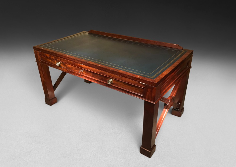 A Regency mahogany library table with a leather writing surface, a low rear gallery, a frieze drawer with brass knobs, and structured end supports. View XI