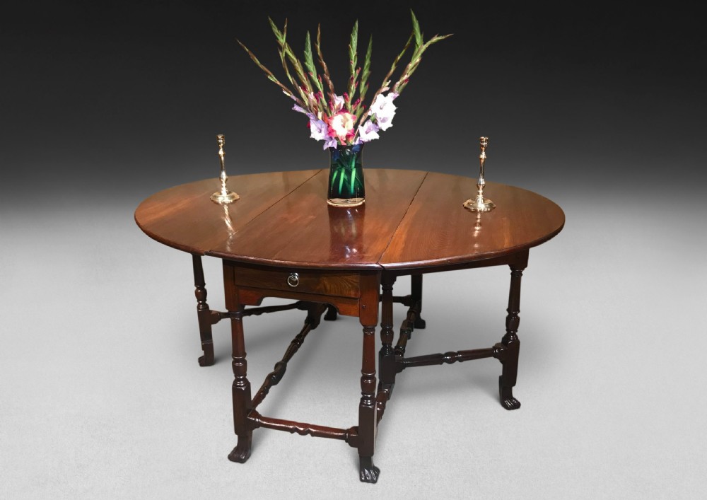 A mahogany Queen Anne gateleg table featuring two drop leaves, turned legs, pad feet, and a central end drawer.