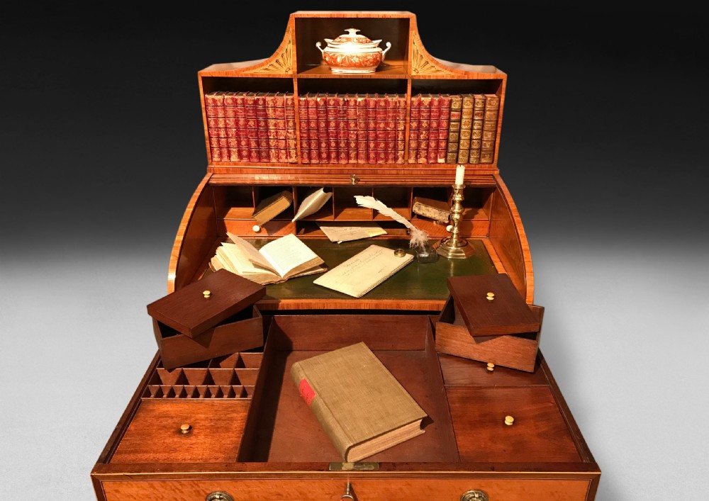 A George III satinwood bonheur du jour desk featuring a curved slatted tambour cover, a raised shelf superstructure with inlaid fan motifs, a single drawer with brass handles, and slender tapered legs on castors. View V