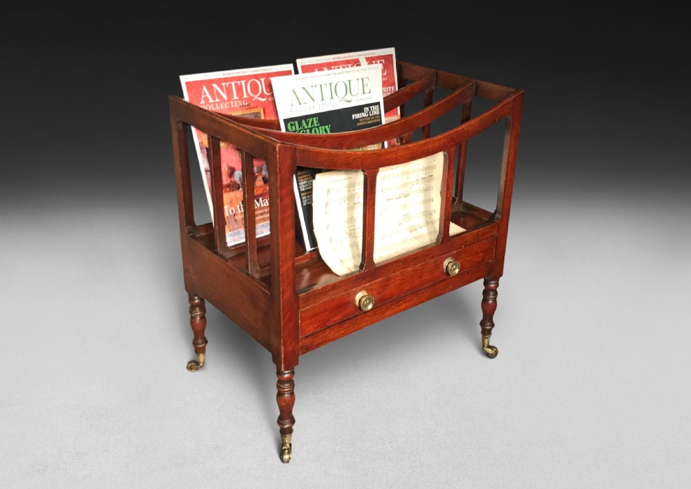 A Regency period mahogany Canterbury featuring three curved compartments, a single lower drawer with brass knobs, turned legs, and brass castors.