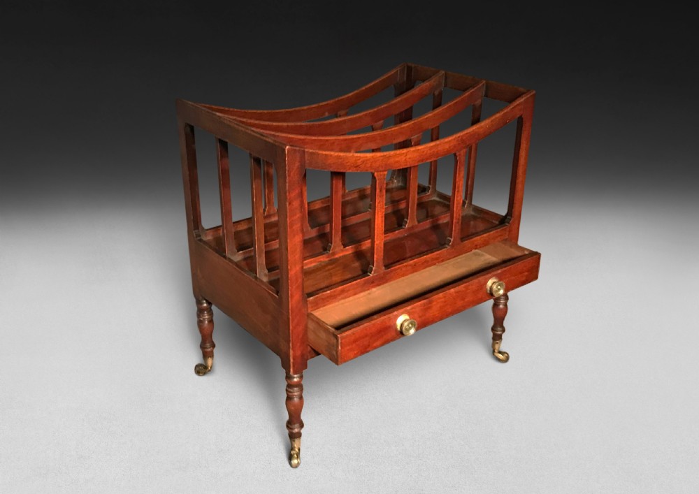 A Regency period mahogany Canterbury featuring three curved compartments, a single lower drawer with brass knobs, turned legs, and brass castors. View II