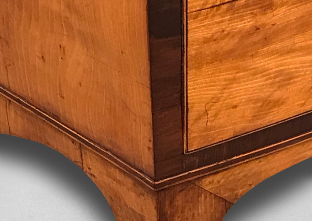 A George III period bowfront satinwood chest of drawers featuring kingwood crossbanding and four graduated drawers on bracket feet. View III