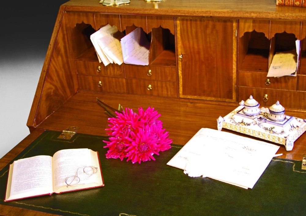 A George III flame mahogany slant-front writing bureau featuring burr yewwood crossbanded borders, four graduated drawers with brass handles, and bracket feet. View IV