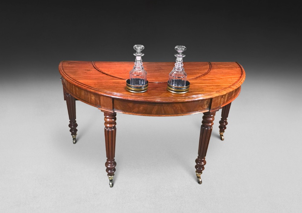 A horseshoe-shaped Regency mahogany hunt table featuring reeded turned legs with brass castors. View III