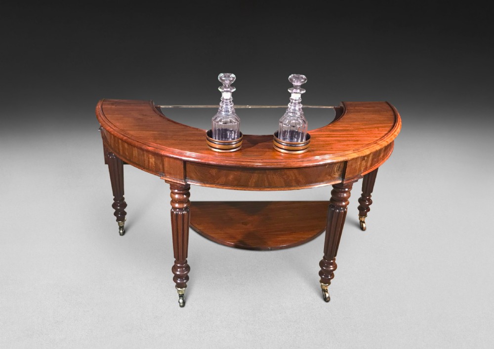 A horseshoe-shaped Regency mahogany hunt table featuring reeded turned legs with brass castors. View V