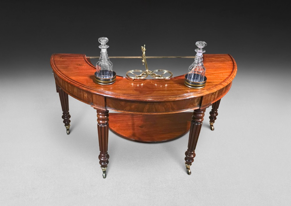 A horseshoe-shaped Regency mahogany hunt table featuring reeded turned legs with brass castors. View VI