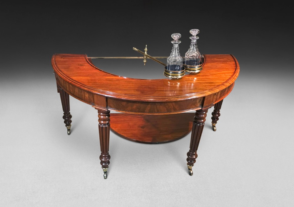 A horseshoe-shaped Regency mahogany hunt table featuring reeded turned legs with brass castors. View VII