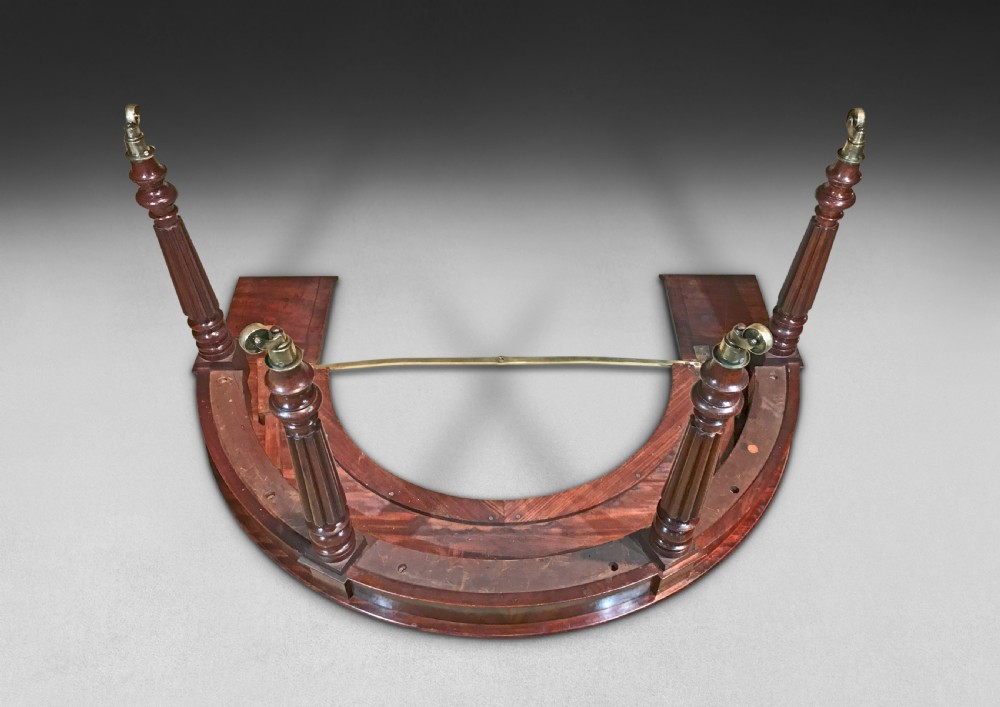 A horseshoe-shaped Regency mahogany hunt table featuring reeded turned legs with brass castors. View XI