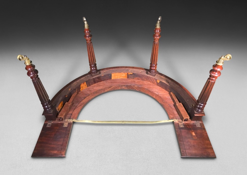 A horseshoe-shaped Regency mahogany hunt table featuring reeded turned legs with brass castors. View XII