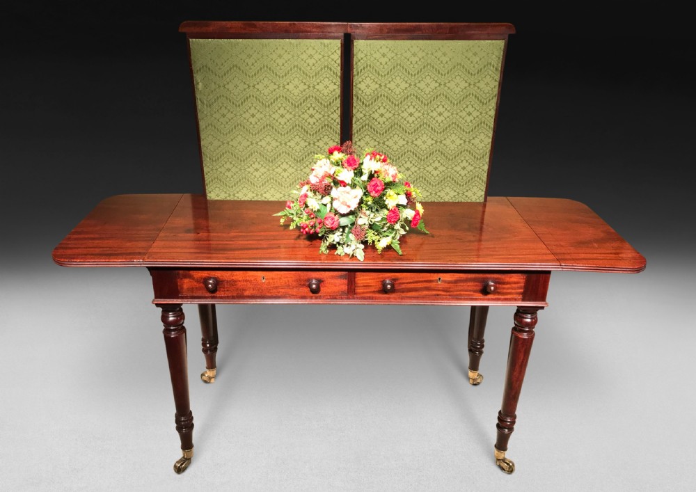 A Regency mahogany sofa writing table featuring two drop flaps, two frieze drawers, turned legs on brass castors, and an adjustable green fabric screen. View II