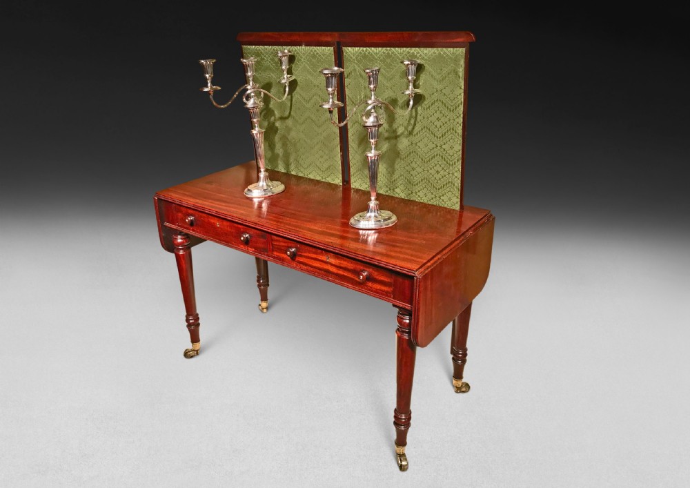A Regency mahogany sofa writing table featuring two drop flaps, two frieze drawers, turned legs on brass castors, and an adjustable green fabric screen. View III