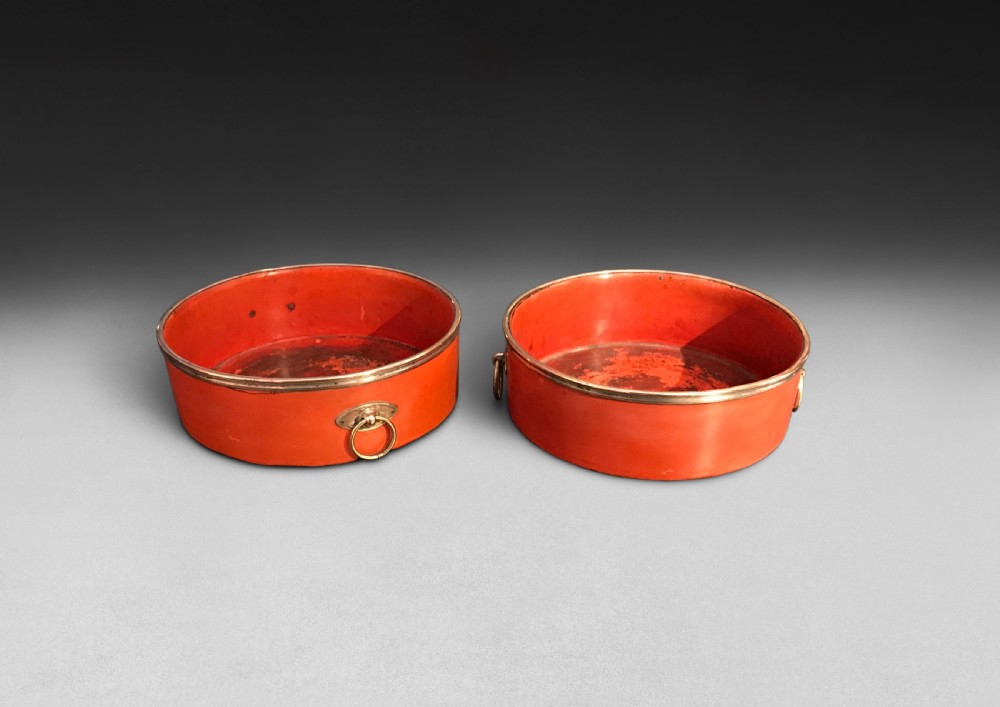 A pair of circular Regency period red papier-mache wine coasters with brass rims and brass side ring handles.