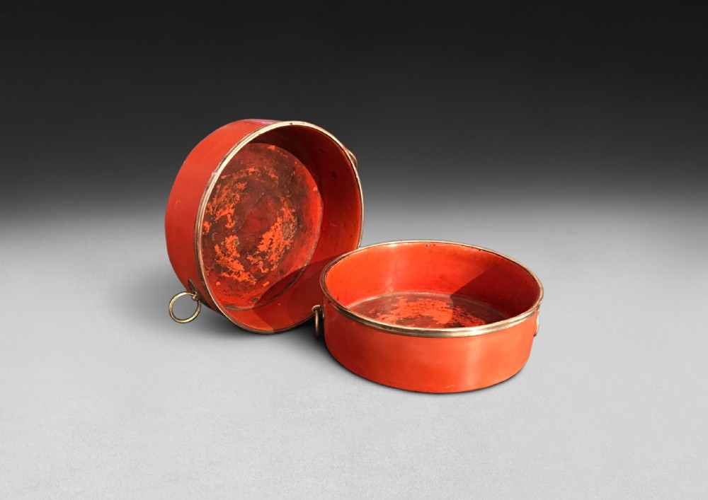 A pair of circular Regency period red papier-mache wine coasters with brass rims and brass side ring handles. View IV