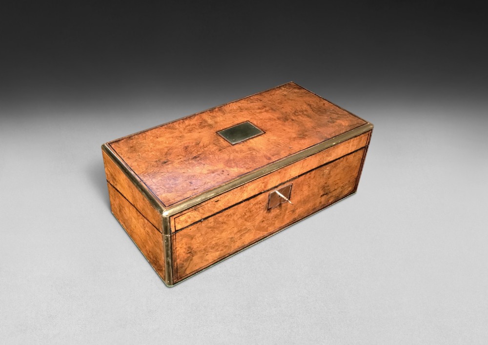 A rectangular burr walnut campaign writing box featuring brass edge banding, corner mounts, an inlaid brass cartouche, and a key escutcheon.