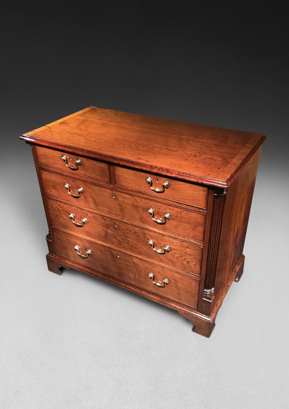 A George III mahogany chest of drawers featuring a two-over-three drawer layout, brass swan-neck handles, reeded corner pilasters, and bracket feet.