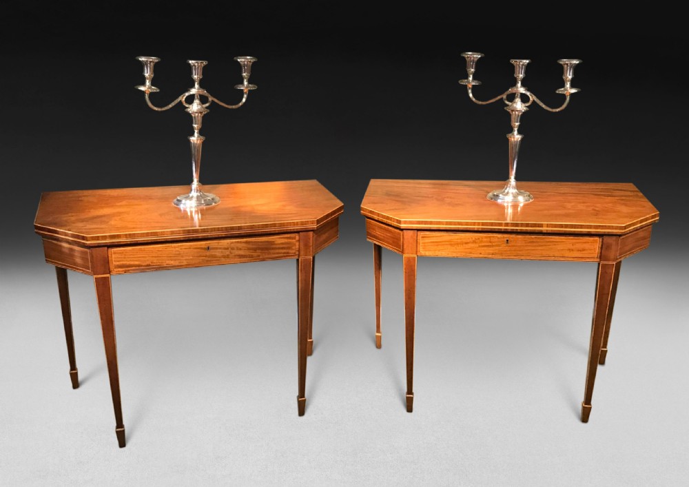 A pair of George III mahogany fold-over card tables with linear stringing inlay and square tapered legs.