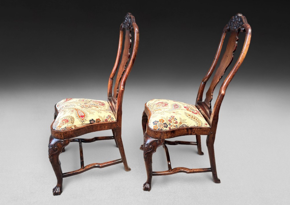 A pair of antique George I walnut side chairs featuring carved cresting rails, vase-shaped back splats, floral upholstered drop-in seats, and cabriole front legs. View II