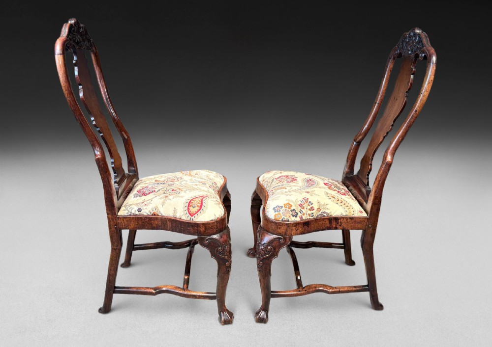 A pair of antique George I walnut side chairs featuring carved cresting rails, vase-shaped back splats, floral upholstered drop-in seats, and cabriole front legs. View IV