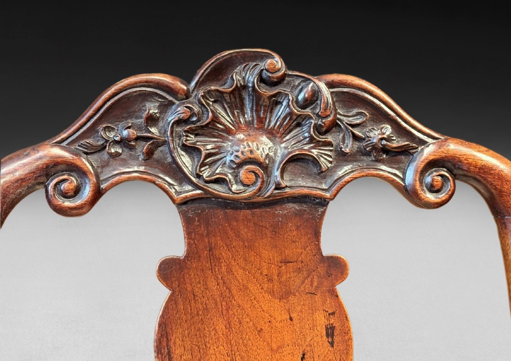 A pair of antique George I walnut side chairs featuring carved cresting rails, vase-shaped back splats, floral upholstered drop-in seats, and cabriole front legs. View VI