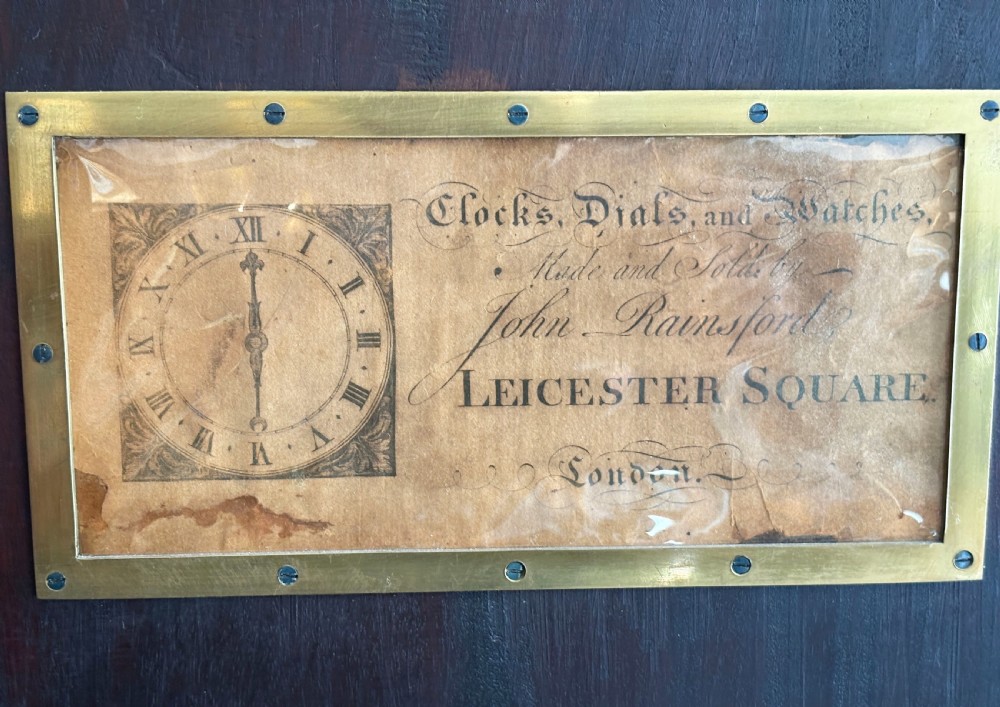 A Georgian longcase clock featuring a polished mahogany cabinet, brass dial with chapter ring, and decorative hood finials. View III