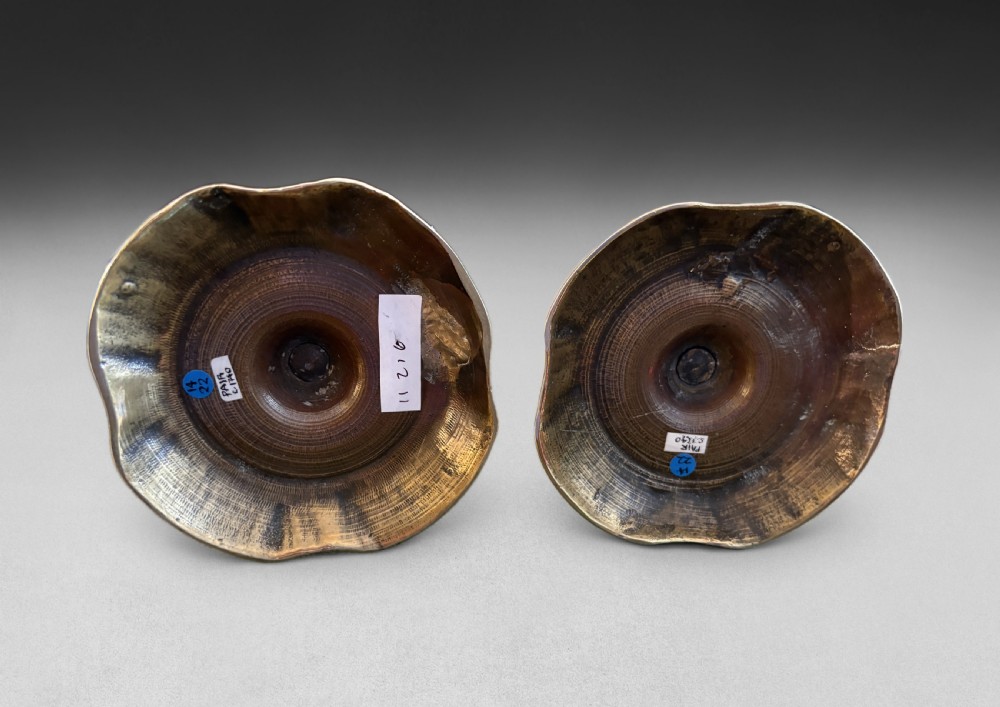A pair of mid-18th century cast brass candlesticks featuring turned baluster stems and shaped scalloped bases. View II