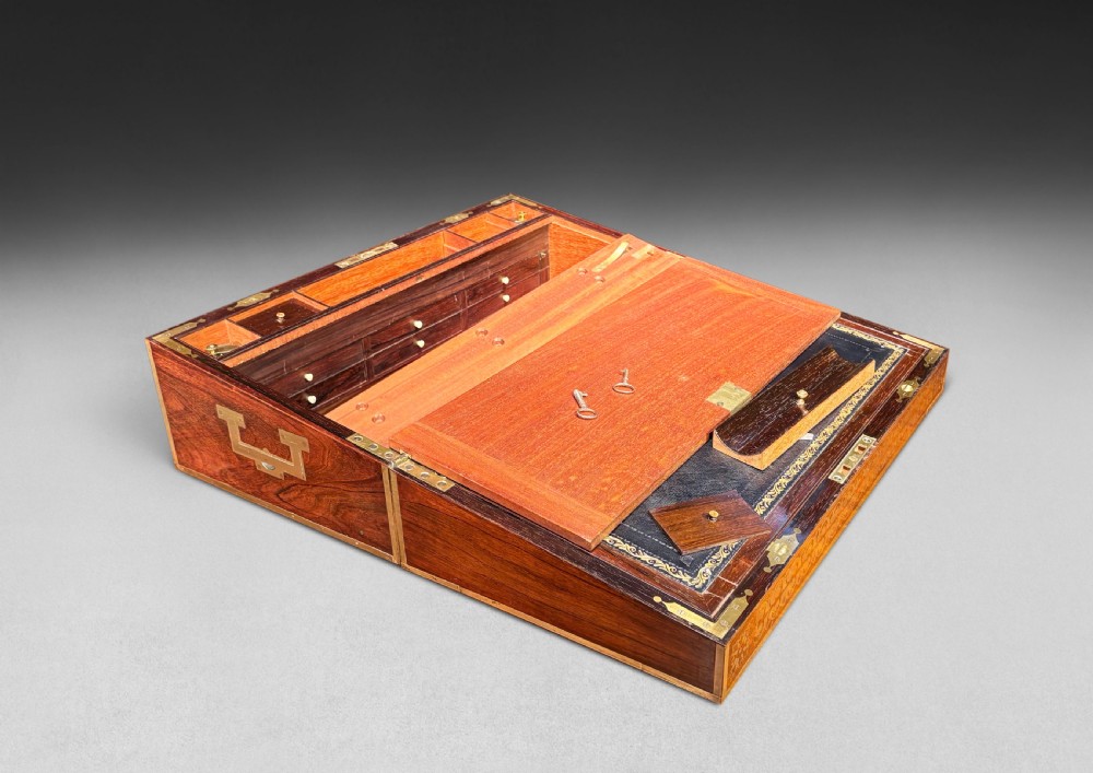 An opened Regency rosewood writing slope featuring brass inlay, brass candle sockets, side handles, and a dark leather writing surface. View III
