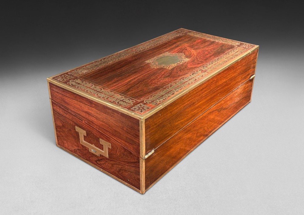 An opened Regency rosewood writing slope featuring brass inlay, brass candle sockets, side handles, and a dark leather writing surface. View IV