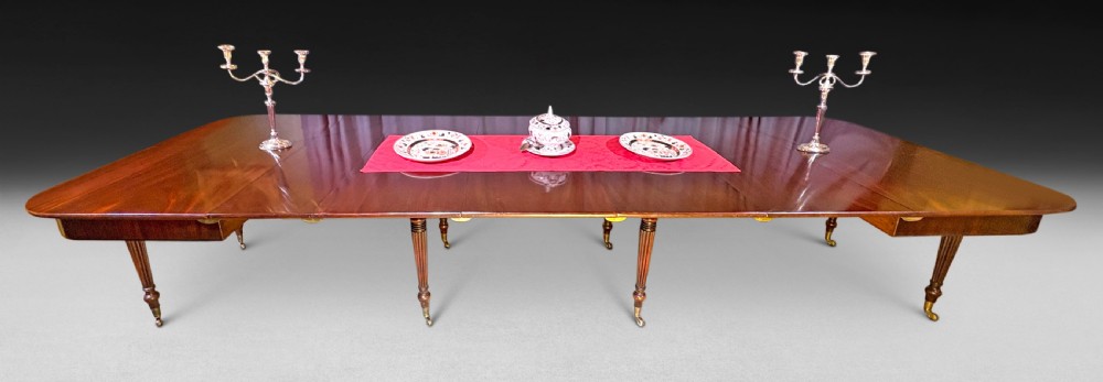 A Regency mahogany extending imperial dining table with reeded turned legs resting on brass castors, fully extended with additional leaves.