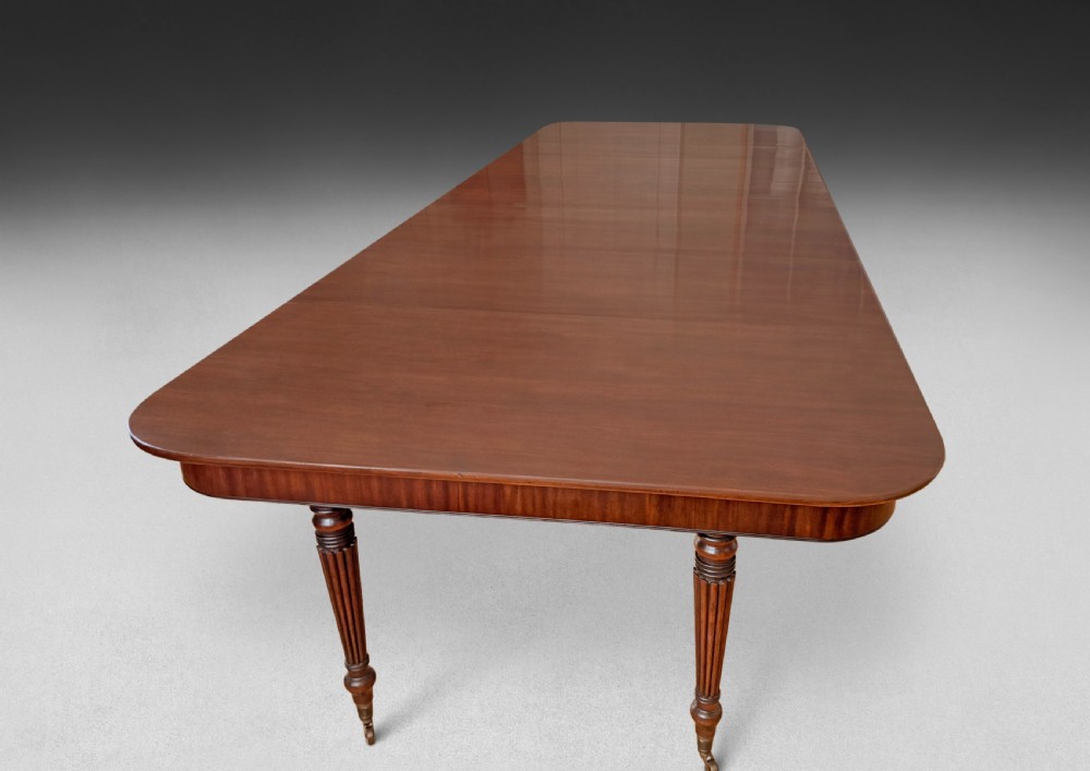 A Regency mahogany extending imperial dining table with reeded turned legs resting on brass castors, fully extended with additional leaves. View V