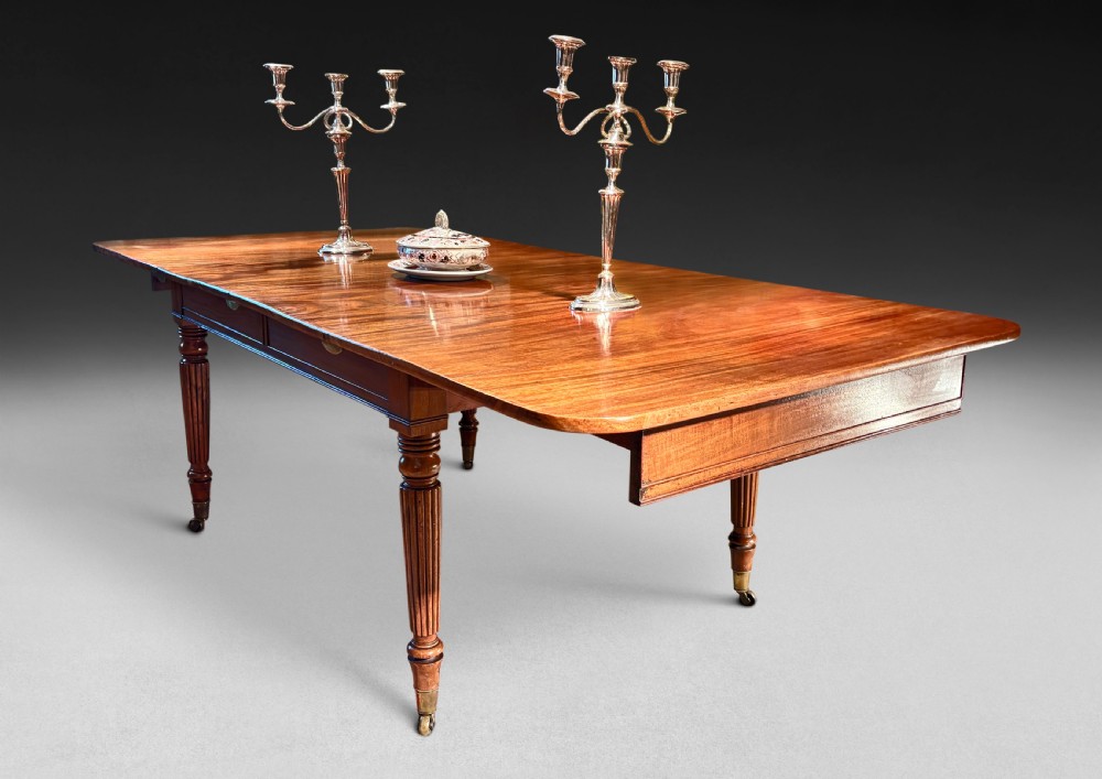 A large Regency period mahogany extending dining table featuring reeded tapered legs resting on brass castors.