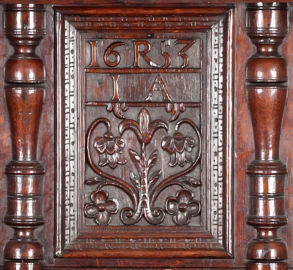 A mid-17th century carved dark oak press cupboard featuring relief-carved upper panels, turned balusters, arcaded lower doors, and an inscribed date of 1653. View IV