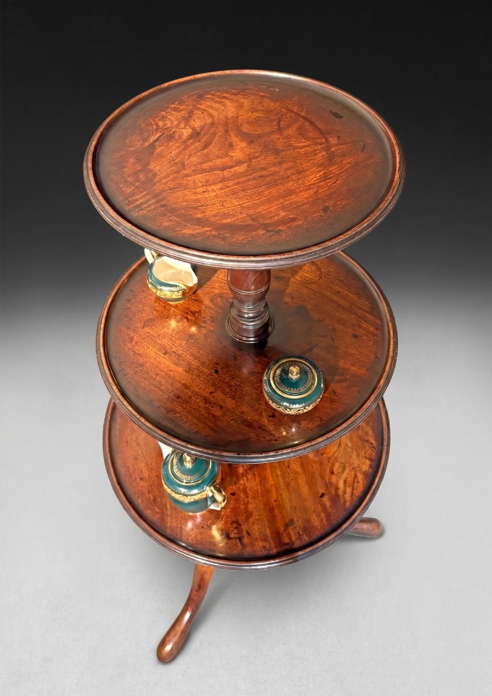 A George III mahogany three-tier dumb waiter featuring graduated circular trays on a turned central column supported by a tripod base. View III