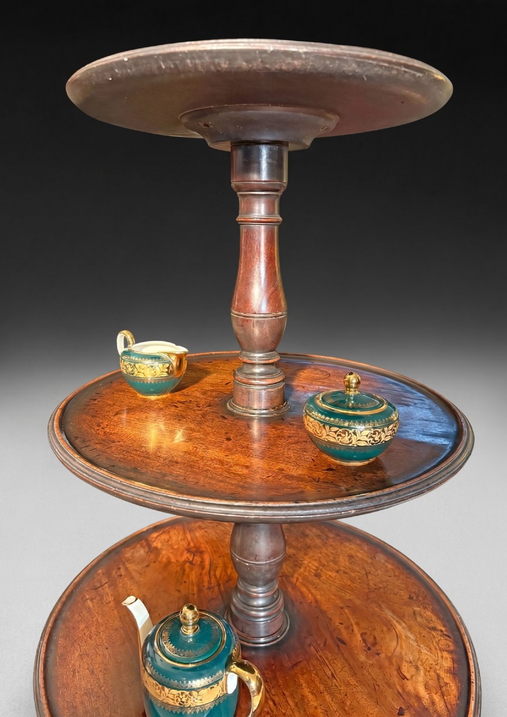 A George III mahogany three-tier dumb waiter featuring graduated circular trays on a turned central column supported by a tripod base. View IV