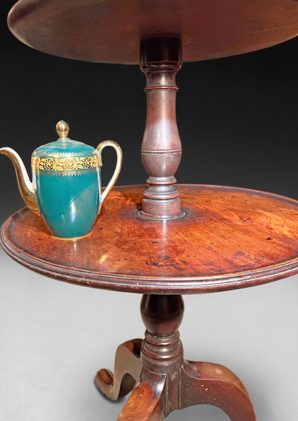 A George III mahogany three-tier dumb waiter featuring graduated circular trays on a turned central column supported by a tripod base. View V