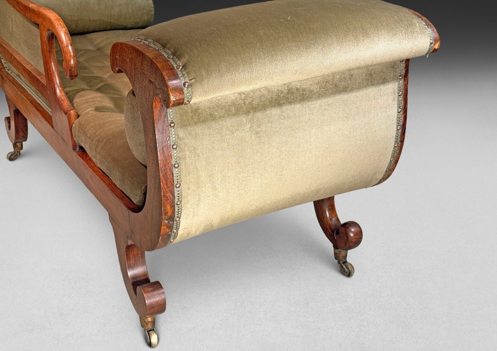 Regency simulated rosewood chaise longue with brass inlay, featuring asymmetrical scroll ends, turned brass-castor legs, olive green button-tufted upholstery, and matching bolster cushions. View VIII