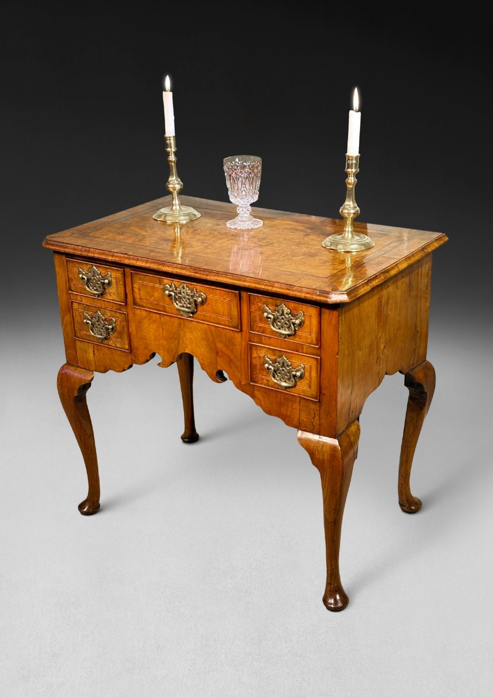 A George II period burr walnut lowboy featuring cabriole legs ending in pad feet, multiple drawers with brass drop handles, and a shaped apron. View V