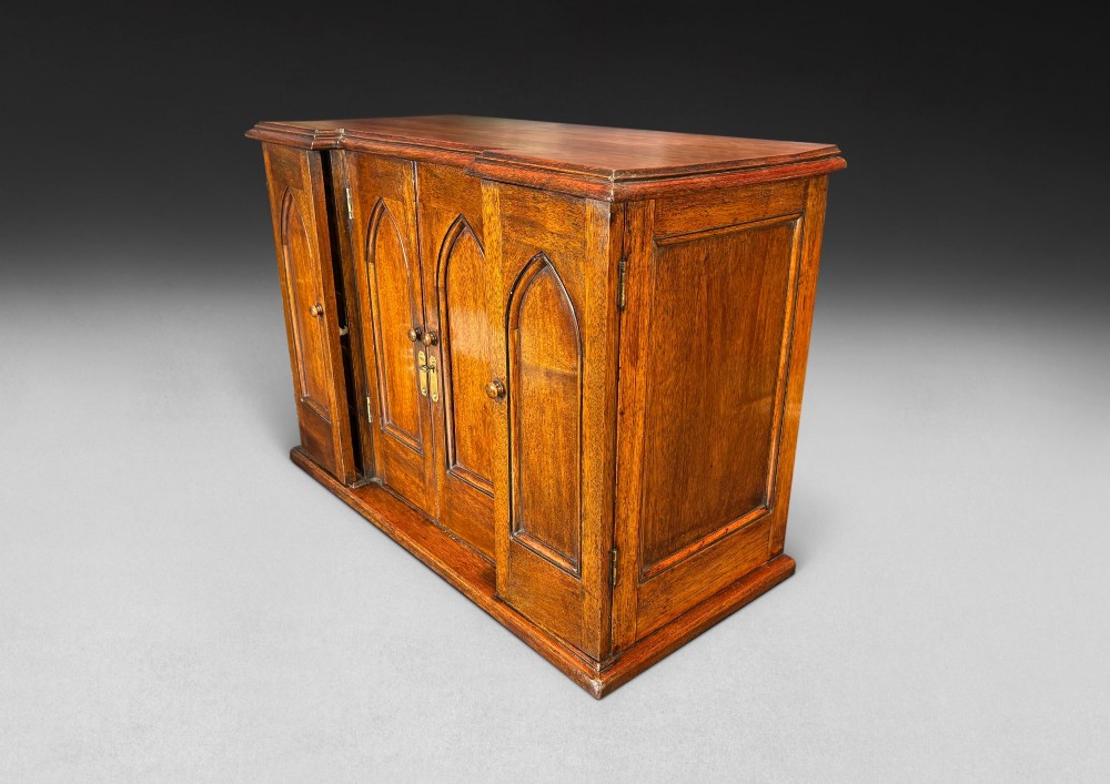 A nineteenth-century oak tabletop collectors cabinet featuring breakfront doors with carved Gothic arch panels and turned wooden knobs. View II