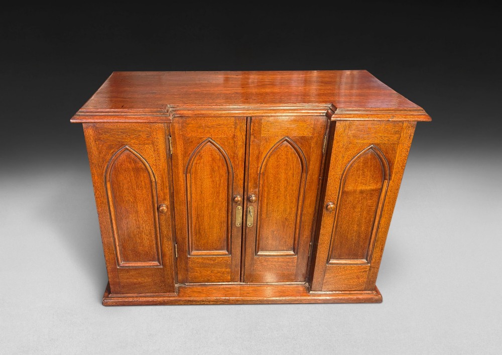 A nineteenth-century oak tabletop collectors cabinet featuring breakfront doors with carved Gothic arch panels and turned wooden knobs. View VIII