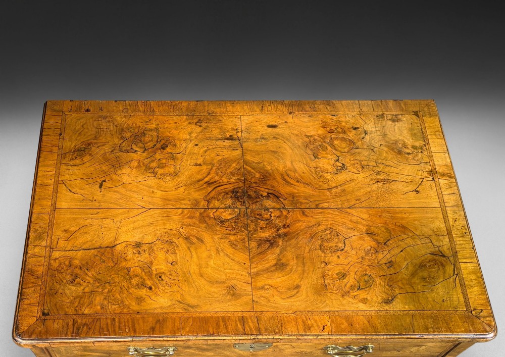 A George I period kneehole desk made from figured walnut with brass drop handles, bracket feet, and a central recessed cupboard. View IV