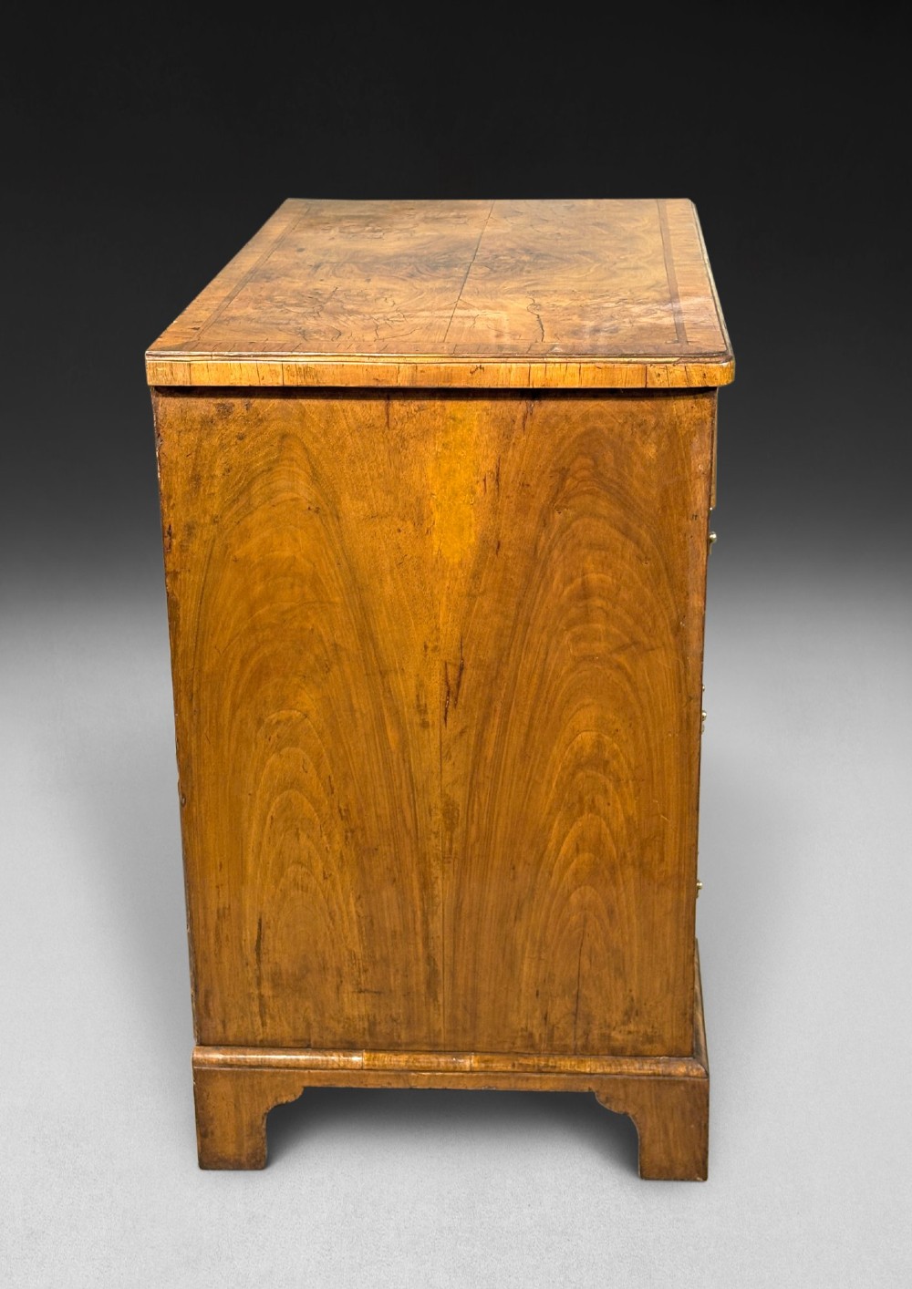 A George I period kneehole desk made from figured walnut with brass drop handles, bracket feet, and a central recessed cupboard. View V