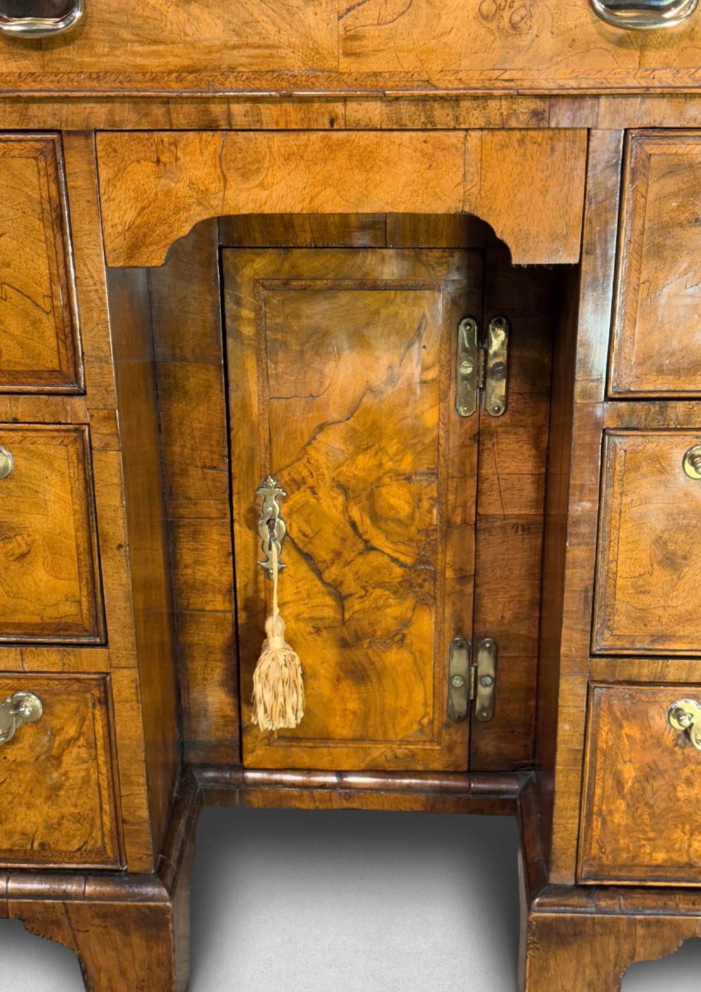 A George I period kneehole desk made from figured walnut with brass drop handles, bracket feet, and a central recessed cupboard. View VII