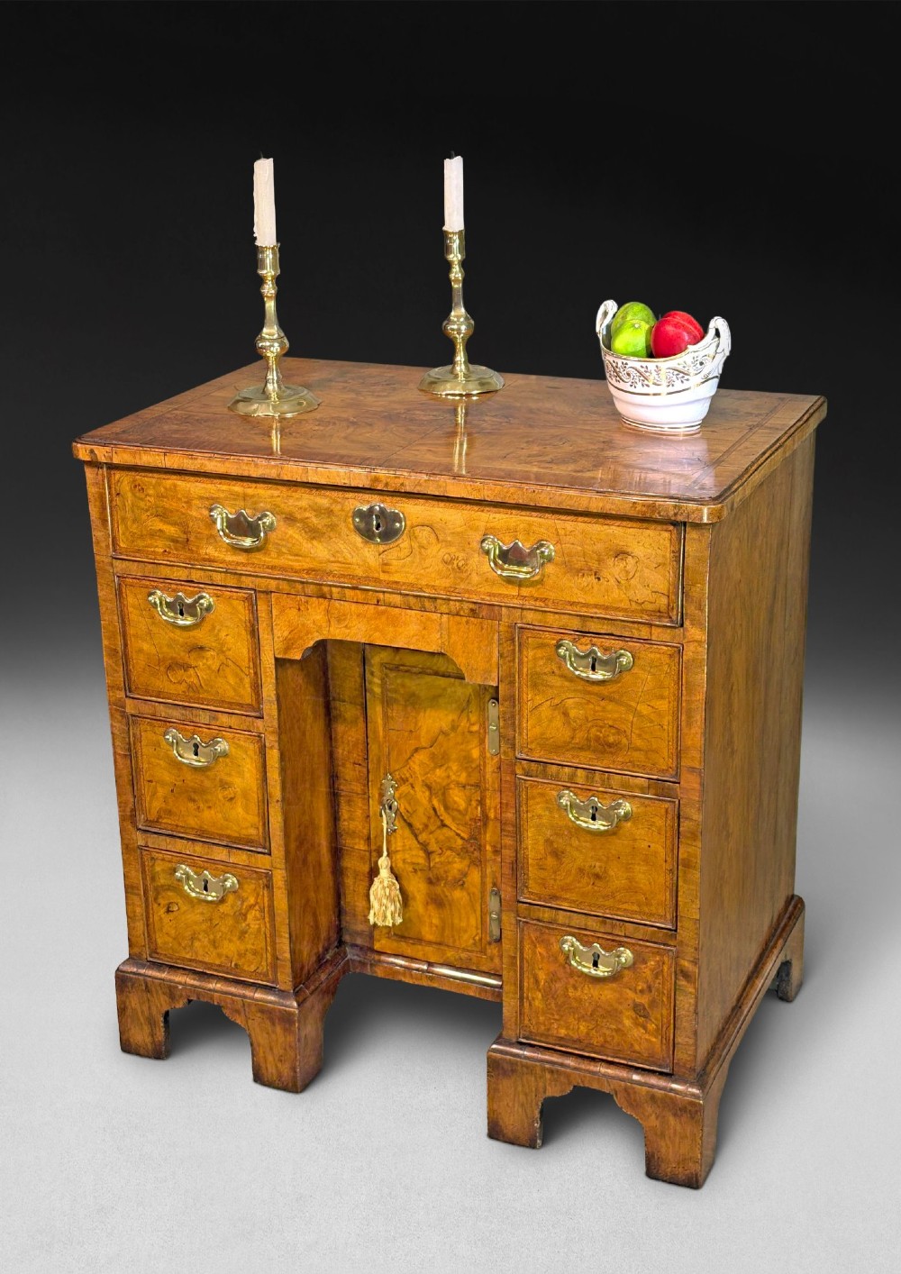 A George I period kneehole desk made from figured walnut with brass drop handles, bracket feet, and a central recessed cupboard. View VIII